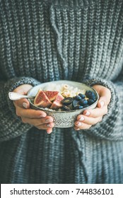 Healthy Winter Breakfast. Woman In Woolen Sweater Holding Bowl Of Rice Coconut Porridge With Figs, Berries, Hazelnuts. Clean Eating, Vegetarian, Vegan, Alkiline Diet Food Concept