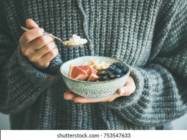 Healthy winter breakfast. Woman in woolen sweater eating rice coconut porridge with figs, berries, hazelnuts. Clean eating, vegetarian, vegan, alkiline diet food concept - Shutterstock ID 753547633
