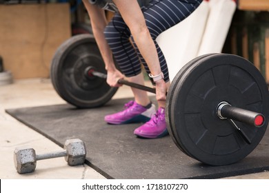 Healthy Woman Performing A Weight Lifting Deadlift Movement In A Home Gym (garage)