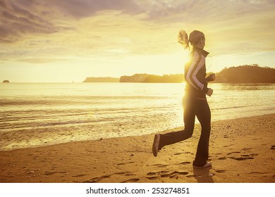 Healthy woman running on the beach at sunset