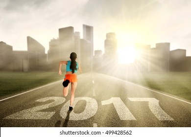 Healthy woman running on the road while wearing sportswear with numbers 2017