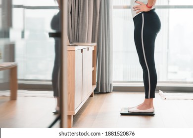 A Healthy Woman Standing On A Scale To Measuring Her Weight In The Living Room After Home Workout In The Morning. Body Mass Index - BMI, Hormones, Weight Loss, Ideal Healthy Weight, Metabolism, Diet.