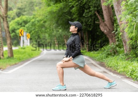 Healthy woman warming up stretching her arms. Asian runner woman workout before fitness and jogging session on the road nature park. Healthy and Lifestyle Concept