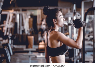 Healthy women in black sport shirt
 are drinking water at the gym. Space on left of photo for your wording.