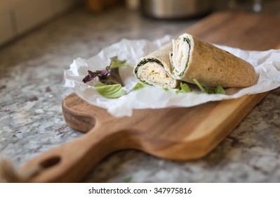 a healthy wrap with turkey, greens and cheese made with whole grain tortilla wrap on wooden board