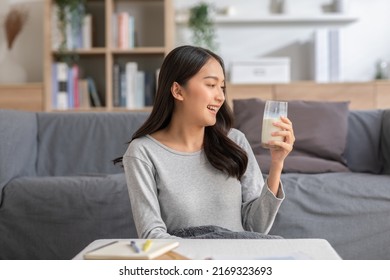 Healthy Young Asian Woman Drinking Milk With Calcium For Strong Bone At Home. Smiling Indian Woman Holding Soy Milk On Glass Enjoy With Nutrition Wellness Life.Wellness With Natural Milk Fresh Concept