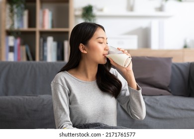 Healthy Young Asian woman Drinking milk with calcium for strong bone at home. Smiling indian woman holding soy milk on glass enjoy with nutrition wellness life.Wellness with natural milk fresh Concept