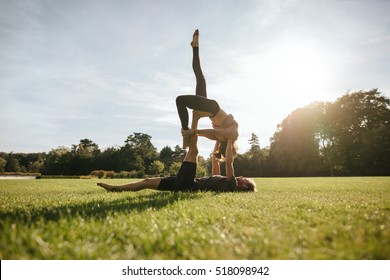 Healthy young couple doing acroyoga in park. Fit young man and woman doing various yoga poses in pair outdoors. - Powered by Shutterstock