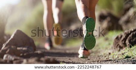 Healthy young couple running on mountain trail in morning. Trail running marathon fitness feet on rock fitness and healthy lifestyle