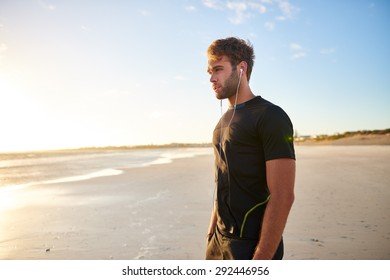 Healthy Young Man In Sports Wear Standing On The Beach On A Bright Morning At Sunrise