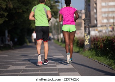 healthy young multiethnic couple jogging in the city on a sunny summer day - Shutterstock ID 523796260