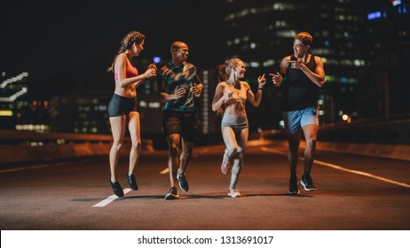 Healthy young people running together in night on street. Runners training together outdoors in evening. - Powered by Shutterstock