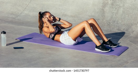 Healthy young woman doing sit ups. Woman in sportswear doing abs workout on fitness mat. - Powered by Shutterstock