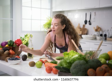 Healthy young woman in a kitchen preparing vegetables for healthy meal and salad - Shutterstock ID 1160637796