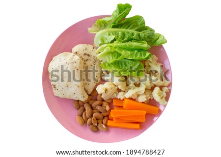 Healty food, close up green salad with almond, steamed carrots and chicken smoked breast on pink ceramic plate.