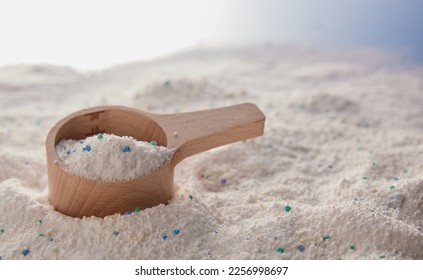 Heap of antibacterial soap powder for daily laundry routine with wooden measuring cup placed on messy table in light studio - Shutterstock ID 2256998697