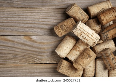 Heap of assorted wine corks on wooden background.