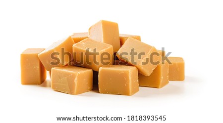Heap of caramel vanilla fudge isolated on white background. Fresh tasty candies made of milk and sugar. Square pieces of delicious chewy soft sweets. Full depth of field. Front view.