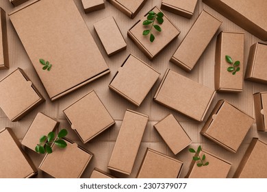 Heap of cardboard boxes from natural recyclable materials with green leaves sprout top view. Responsible consumption, eco friendly packaging, zero waste concept. - Shutterstock ID 2307379077