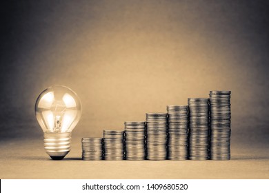 Heap coins stair and small light bulb glowing on brown background with copy space, SME or SMB, start business to success, budget or financial concept