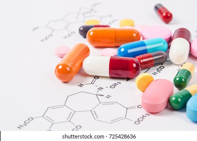 Heap of color pills and tablets on chemical formulas background