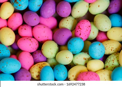 A heap of colourful speckled eggs. Lots of small pink, purple, blue, yellow and green candy coated chocolate eggs. - Powered by Shutterstock