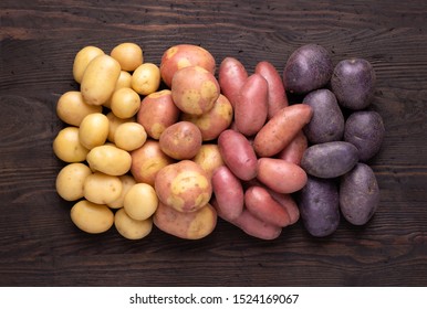 Heap of different types of potatoes on dark wooden rustic table