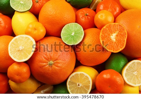 A heap of mixed citrus fruit including   lemons, limes, grapefruit and tangerines with slices, top view