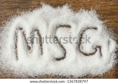 Heap of monosodium glutamate on wooden background with text MSG