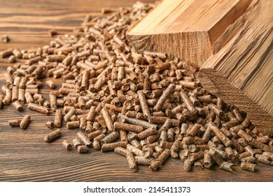 Heap of pellets with firewood on wooden background, closeup