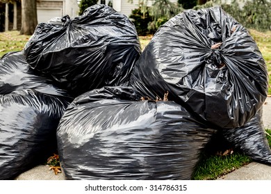 Heap Of Plastic Trash Bags On Curb Waiting For Sanitation Pickup