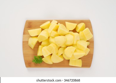 heap of raw diced potatoes on wooden cutting board