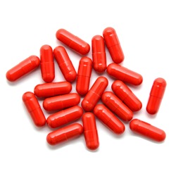 Heap Of Red Pills Isolated On White Background. Macro. Tablets Scattered On A Table. Pharmacy. Treatment. 