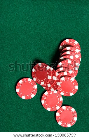 Heap of red poker chips on the green table. Symbol of risky entertainment