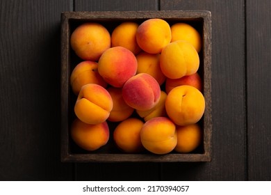 Heap of ripe apricots in wooden box on wooden table background. Top view. Close up. - Shutterstock ID 2170394057