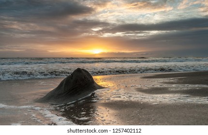 A heap of sand has formed on the beach at Cococoa, Florida, whil the sun is dramatically breaking through the clouds.