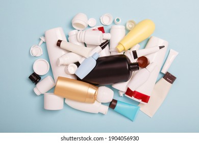 heap of separate collection of HDPE bottles from cosmetics for recycling. High-Density Polyethylene recyclable cosmetics package on blue background. Plastic garbage. Save the planet