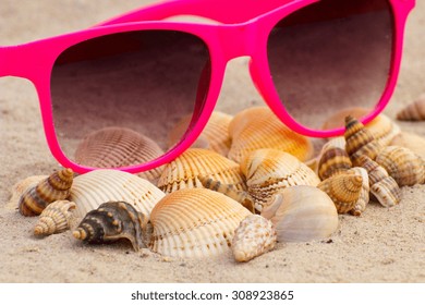 Heap Of Shells And Pink Sunglasses Lying On Sand At The Beach, Vacation And Summer Time, Eye Protection