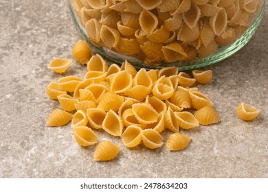 Heap of uncooked shell pasta with a glass jar close up - Powered by Shutterstock