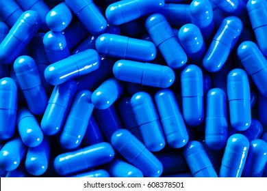 Heap of vivid blue capsule pills close up background