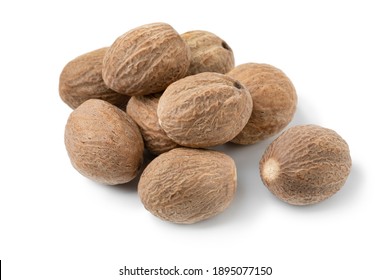 Heap of whole dried nutmeg seeds close up isolated on white background