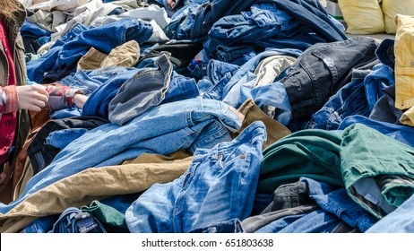 Heaps of clothing on the second hand market. Pile of second hand clothes at a garage sales. The hand digs into the heap of clothes