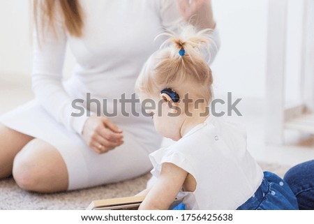 Hearing aid in baby girl's ear. Toddler child wearing a hearing aid at home. Disabled child, disability and deafness concept. Foto stock © 