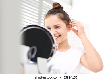 The Hearing Aid For A Child. Cheerful Girl Assumes Hearing Aid Viewing In The Mirror 