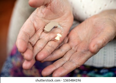 a hearing aid on the palms of an old woman - Powered by Shutterstock