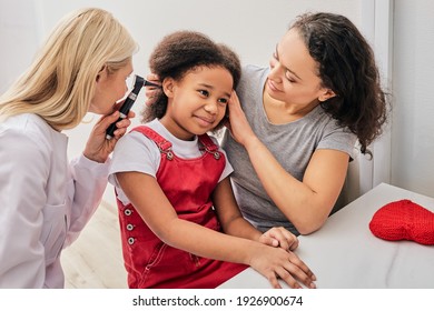 Hearing Exam. Child With Her Mother During A Hearing Test, Audiologist With Otoscope Checking Ear Of A Little Patient