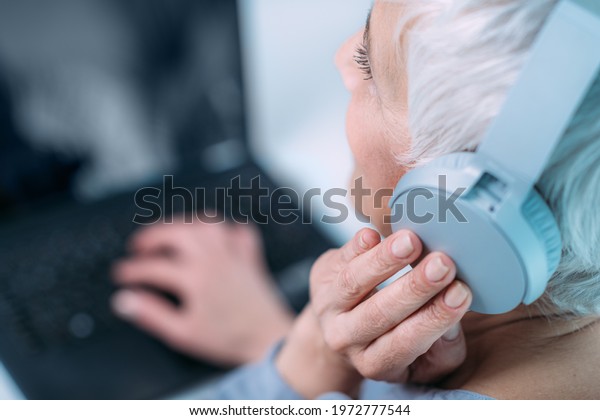 Hearing test or audiogram. Senior woman\
self-testing hearing ability with\
laptop