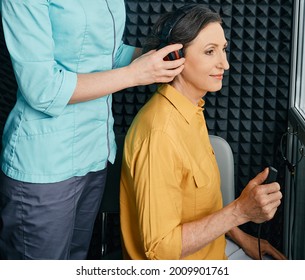 Hearing Test To Mature Woman. Senior Woman During Hearing Test And Audiometry At Hearing Clinic With Audiologist. Side View