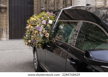 Hearse with floral wreath. Ritual funeral services in a European city.