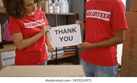 In the heart of activism, man and woman volunteers at charity center standing united, holding 'thank you' message. young, beautiful community workers in t-shirts, showing gratitude amidst donations. - Powered by Shutterstock - Get 15% off with code: PIKWIZARD15